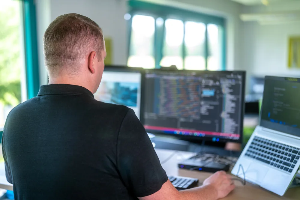 KI-gestützte Softwareentwicklung — Entwickler an Dual-Monitor-Setup bei nu:version